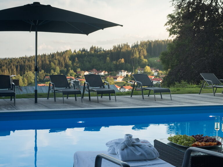 Ein einladender Swimmingpool, umgeben von hochwertigen Gartenmöbeln im luxuriösen Hotelgarten.