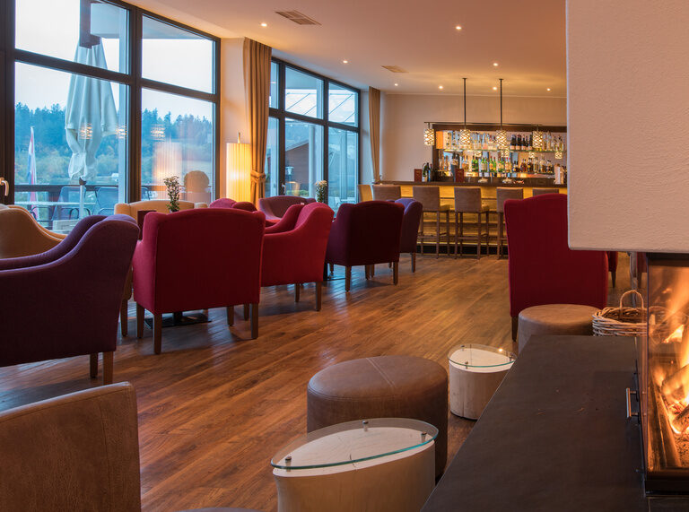 Ein Kamin in einem modernen Restaurant im Hotel mit einer Bar im Hintergrund